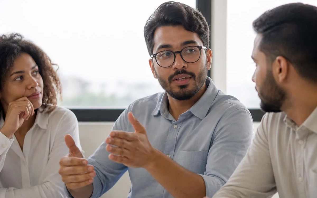 Roda de conversa numa sala clara, com uma pessoa expondo o ponto e duas escutando